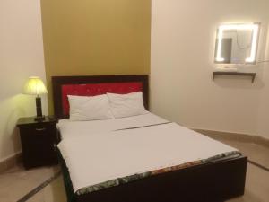 巴哈瓦尔布尔Regal Guest House的一间卧室配有一张带白色床单和红色床头板的床。