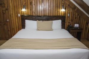 Alto del RobleHotel El Tirol的卧室配有一张白色大床和木墙