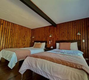 Alto del RobleHotel El Tirol的木墙客房的两张床
