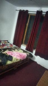 卡尔吉尔OYO Holidayinn的一间卧室配有床和红色窗帘的窗户