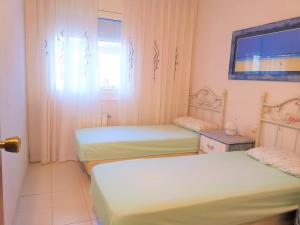 圣萨尔瓦多HOSTEL ALOHA a 3 calles del Mar的客房设有两张床、一台电视和一扇窗户。