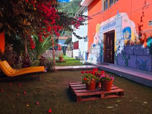 乌鲁班巴Valle verde, Hostel & camping的建筑前木平台上两朵盆花