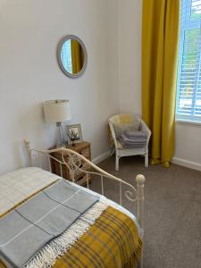 斯特灵Castle Brae Apartment的一间卧室配有一张床、一把椅子和镜子