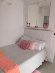 宏达海滩Casa Yurena的一张带粉色和白色枕头的床和镜子