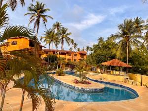 TucacasUn Oasis entre Olas y Palmeras con Playa Privada的一个带游泳池和棕榈树的度假村
