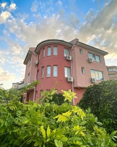 旧扎戈拉马尼尔家庭酒店的前面有灌木丛的粉红色建筑