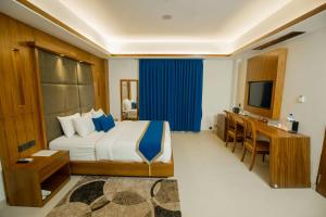 新德里Hotel Aurora Mirage Delhi的一间卧室配有一张床、一张书桌和一台电视