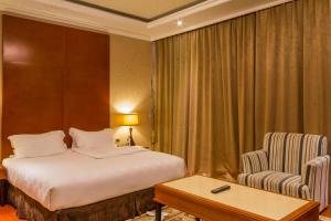 新德里Hotel Aurora Mirage Delhi的配有一张床和一把椅子的酒店客房