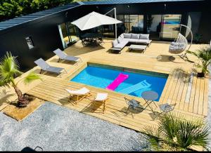 奥登河畔的布雷特维尔Evasion tropicale的后院设有游泳池以及带椅子和遮阳伞的甲板。
