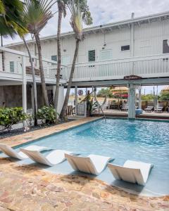 拉帕尔格拉拉甲玛卡宾馆的一个带白色椅子和棕榈树的游泳池