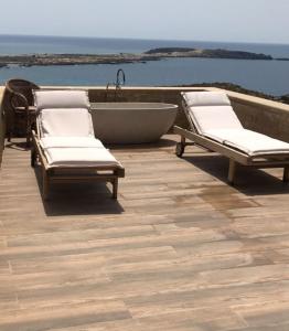 埃拉福尼西岛Elafonisi Villa above the Beach的两把躺椅和一个位于甲板上的浴缸