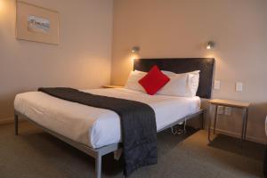 惠灵顿维多利亚苑汽车旅馆的一间卧室配有一张带红色枕头的大床