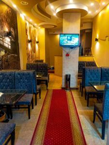 索哈杰Dahab hotel的一间设有椅子、电视和红色地毯的等候室