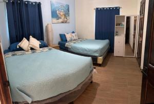 Barra de SantiagoCasa del Sol, Barra de Santiago的配有蓝色窗帘的客房内的两张床
