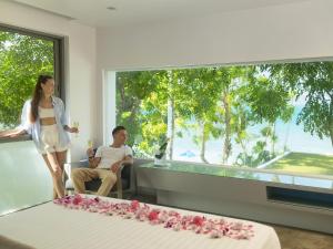 哈林海滩Explorar Koh Phangan - Adults Only Resort and Spa的站在男人旁边,坐在有床的房间的女人