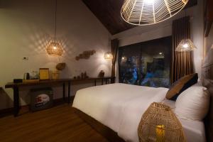 和平Vayang Retreat and Camping的卧室配有一张白色大床和两个灯