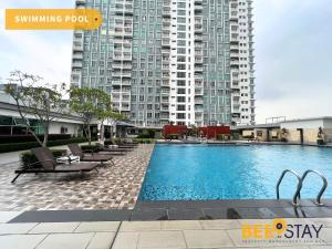 JenjarumBandar Saujana Putra 8PAX Residence Pool View的一个带椅子的游泳池以及位于后面的建筑