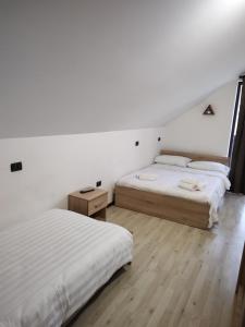 博尔沙Vila Puiu Borsa MM的配有白色墙壁和木地板的客房内的两张床