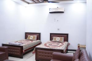 拉合尔Mohal's House的一间设有两张床和一张沙发的房间