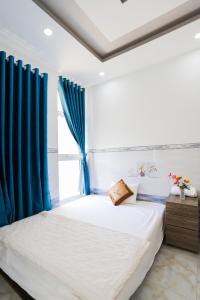 Nhơn TrạchHotel Trâm Anh的一间卧室配有蓝色窗帘的床