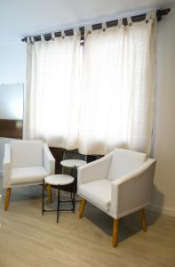 圣保罗Edifício Flat Hotel Congonhas的两把白色的椅子和一张桌子,位于窗户前