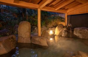 富士河口湖Motosu Phoenix Hotel的一座有岩石和建筑的水池