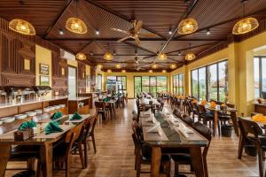 Hương Bá ThướcCentral hills Puluong resort的餐厅设有木桌、椅子和窗户。