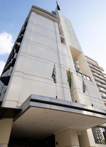 圣保罗Edifício Flat Hotel Congonhas的一座高大的白色建筑,上面有两面旗帜