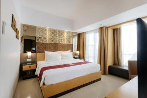 塞米亚克Horison Ultima Seminyak Bali - CHSE Certified的酒店客房设有一张大床和一张沙发。