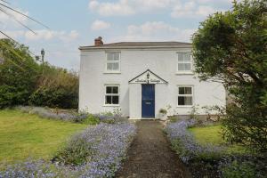 波特里斯Incline Cottage的白色的房子,有蓝色的门和紫色的鲜花