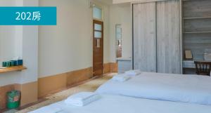Dalin成都旅社民宿的配有书桌的客房内的2张白色床
