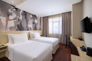 沙努尔Four Star by Trans Hotel的一间酒店客房,设有两张床和电视