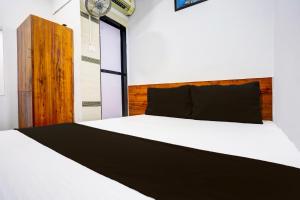 孟买Hotel Metro House的卧室配有白色的床和木制床头板