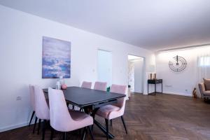 荷兹利亚Stylish 4BR Villa - Herzliya Pituah的一间用餐室,配有黑桌和粉红色的椅子