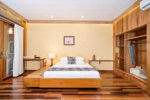 白马市凉廊自然度假酒店的一间卧室设有一张大床,铺有木地板。