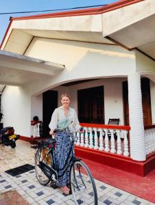 尼甘布Ceylon Glory Hostel的站在房子前面的男人和自行车