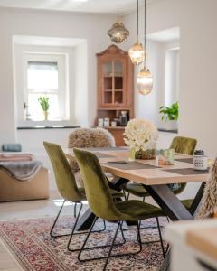 波德科伦AVA HOUSE的一间带桌子和绿色椅子的用餐室