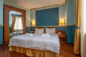布拉格Hotel Kinsky Fountain的一间卧室配有一张白色大床和蓝色的墙壁