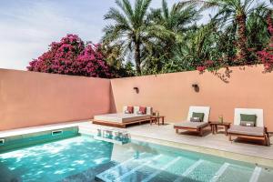 迪拜Meliá Desert Palm Member of Meliá Collection的一个带两把躺椅的游泳池,位于墙上