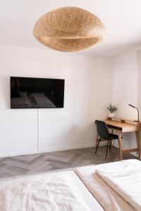 TrierweilerTRIMOSA Apartments - cozy, modern und citynah的一间卧室配有一张床、一张书桌和一个吊灯。