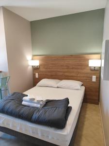 滨海贝尔克露台酒店的一间卧室配有一张大床和木制床头板