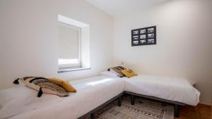 波瓦-迪瓦尔津Casas do Pescador by LovelyStay的配有2张床的白色墙壁和窗户。