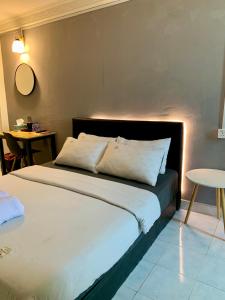 哥打巴鲁Andiana Hotel & Lodge - Kota Bharu City Centre的一间卧室配有一张带白色床单和一张桌子的床。