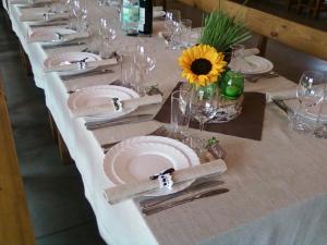 Duokiškissodyba Vieversynė的长白桌子,带盘子和玻璃杯,还有向日葵