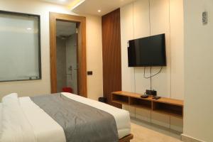 瓜廖尔Hotel maxsun gwalior的一间卧室配有一张床和一台平面电视