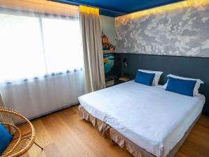 圣米歇尔山圣米歇尔山美居酒店的卧室配有带蓝色枕头的大型白色床