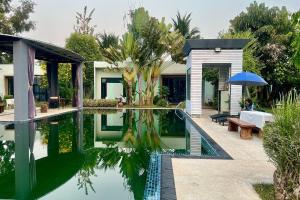 清迈Thai Good Arts Resort的一座带游泳池、桌子和遮阳伞的房子