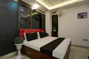新德里OYO Kashish Residency的一间卧室配有一张带黑色和红色枕头的床