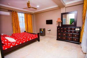 塔科拉迪Thy favour hotel的一间卧室配有红色的床、梳妆台和镜子