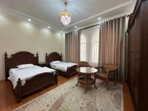 杜尚别Hello Dushanbe Hostel的一间卧室配有两张床、一张桌子和一个吊灯。